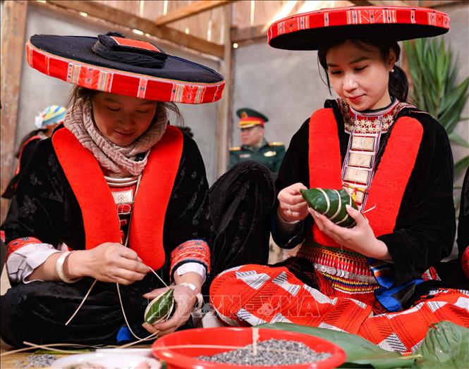 Nữ du khách tới từ Hà Nội trong trang phục truyền thống của người Dao đỏ huyện Nguyên Bình háo hức cùng gói bánh chưng gù ngày Tết. Ảnh: Thanh Tùng - TTXVN